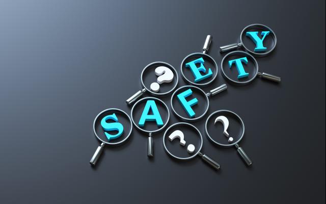 Het woord 'Safety' omringd door vraagtekens. Op elke letter en vraagteken ligt een vergrootglas.