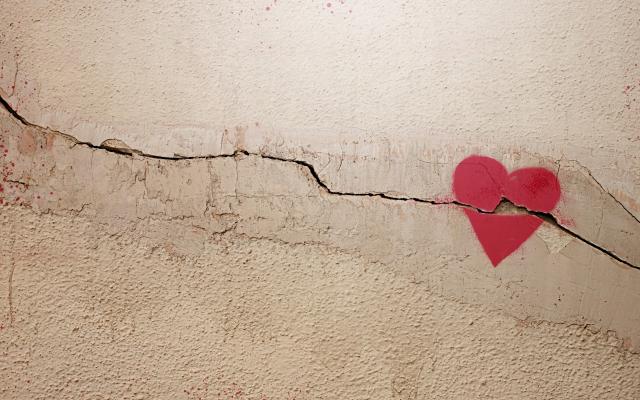 Een getekend hart op een muur of vloer. De ondergrond is gebarsten en de barst loopt door het hart heen.