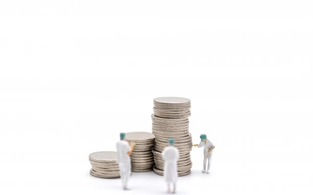 Drie poppetjes staan naast stapels munten.