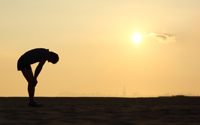 Buigende persoon bij een zonsondergang