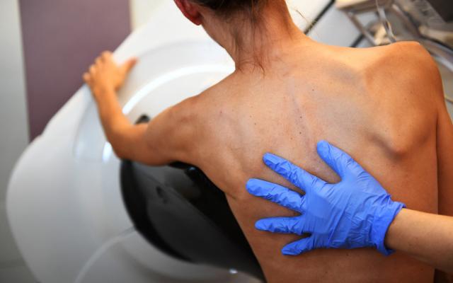 Een hand met een blauwe handschoen op een blote rug.