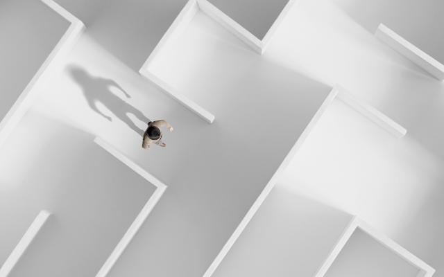 Een persoon in een wit doolhof van bovenaf gezien.