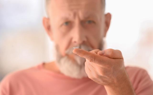 Een man houdt een lens op zijn vingertopje.