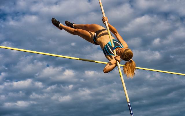 Een polsstokspringer tegen een bewolkte lucht.