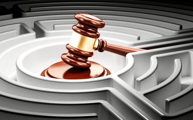 Een voorzittershamer geplaatst in het midden van een doolhof.