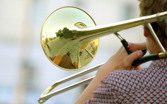 Iemand draagt een trompet op zijn schouder.