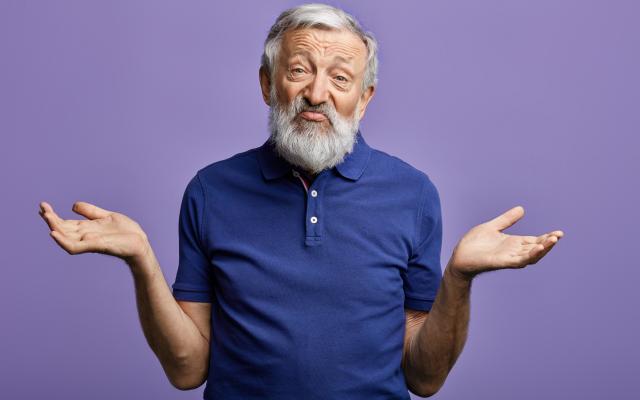 Een oudere man haalt zijn schouders op.