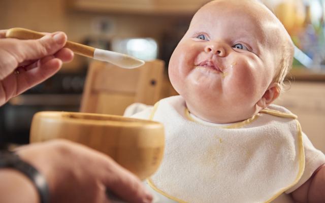 Baby met blauwe ogen wordt gevoerd.