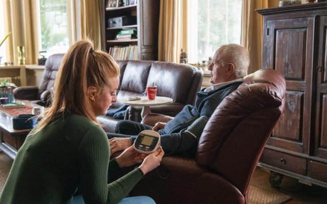 Een verzorger die bloeddruk meet bij oudere