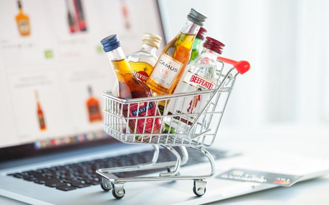 Een mini winkelkarretje vol met drank op een laptop