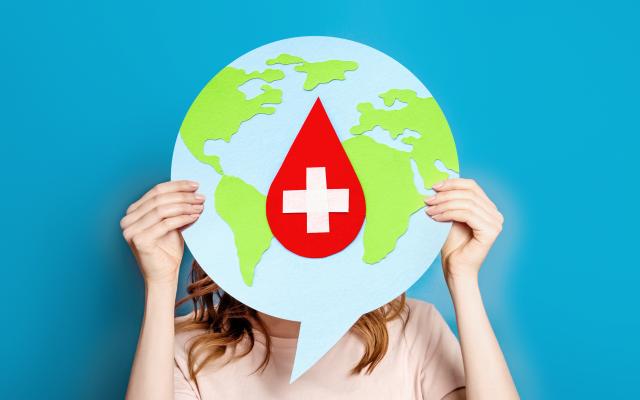 Een vrouw met een tekstballon daarop de wereld en een rood kruis in de vorm van een druppel