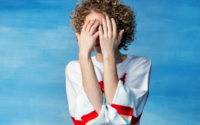 Een persoon die het gezicht met handen afdekt 