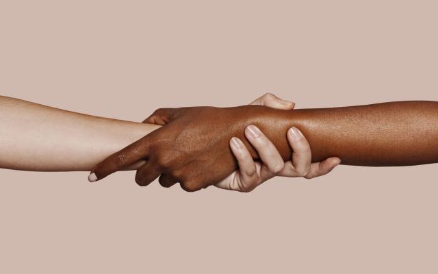 Een zwart en witte hand die elkaar vastpakken