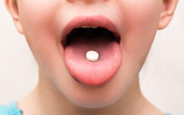 Een uitgestoken tong met een pil erop