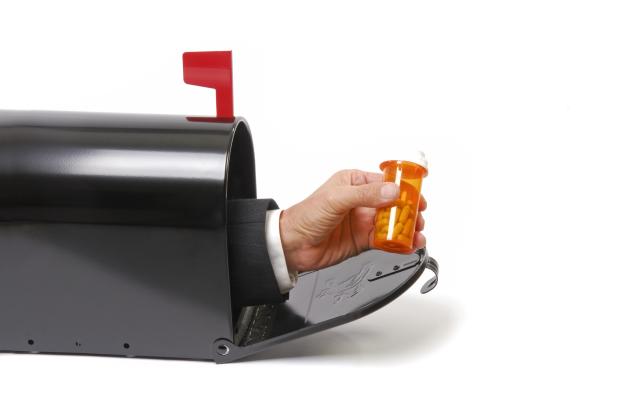 Een hand die vanuit een brievenbus pillen aanbiedt