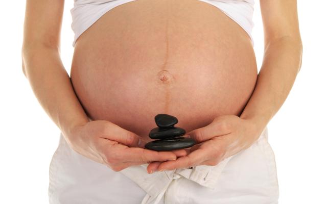 Vrouw met stenen in de hand voor zwangere buik