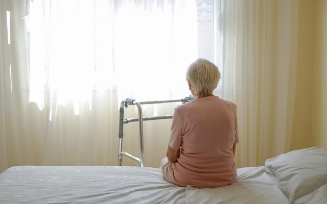 Oude vrouw op ziekenhuisbed met rollator voor zich