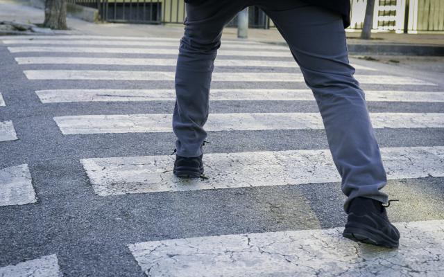 Iemand die een grote stap op een zebrapad neemt