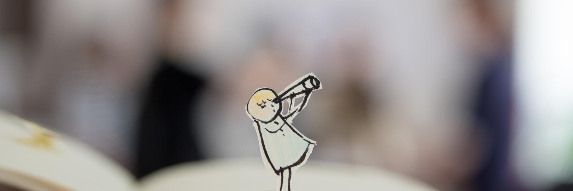 Getekend poppetje staat in een opengeslagen boek.