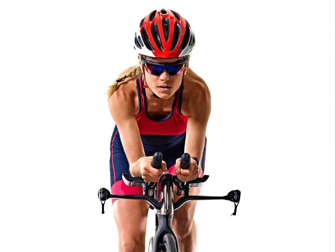 Een wielrenner zit voorover gebogen op haar fiets.