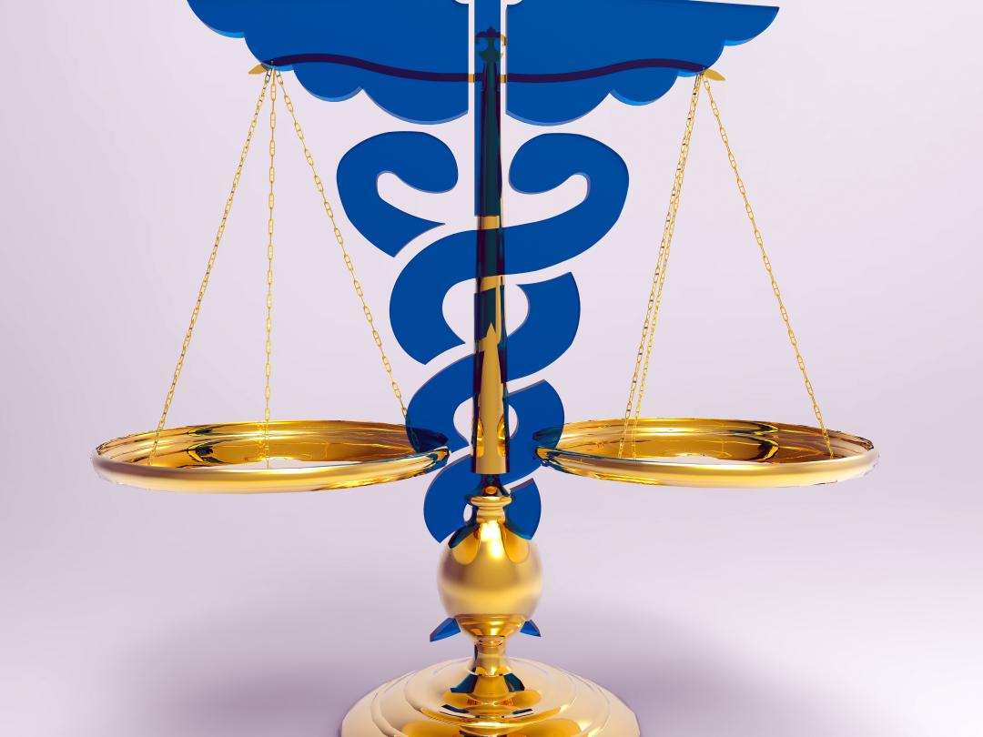 Een weegschaal met het symbool van de caduceus erachter.