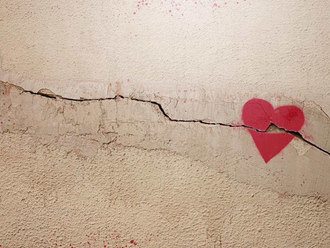 Een getekend hart op een muur of vloer. De ondergrond is gebarsten en de barst loopt door het hart heen.