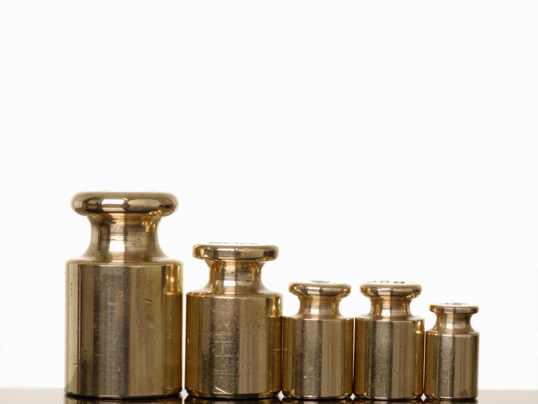 Een set weegschaalgewichten op een rij van groot naar klein.