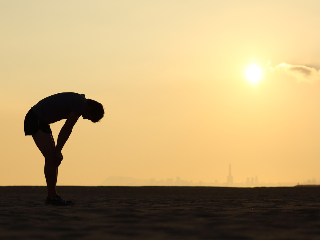 Buigende persoon bij een zonsondergang