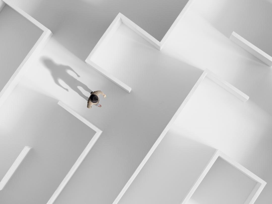 Een persoon in een wit doolhof van bovenaf gezien.