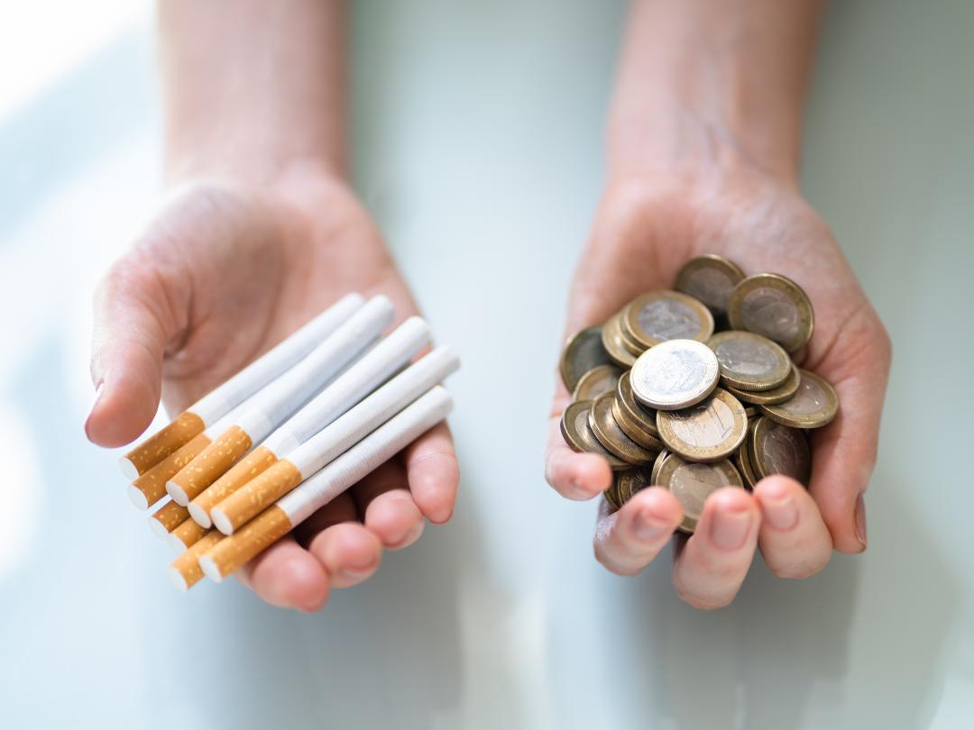 Eén hand gevuld met sigaretten. de andere met geld