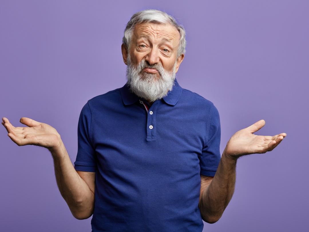 Een oudere man haalt zijn schouders op.