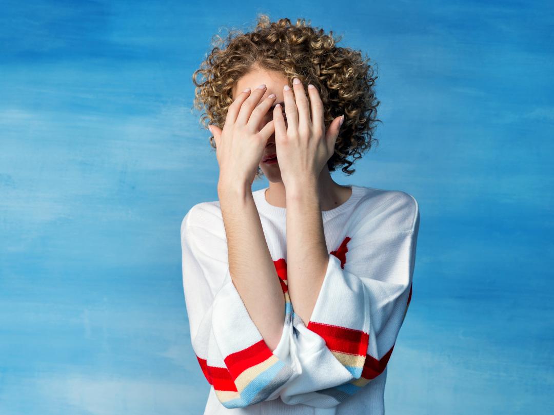 Een persoon die het gezicht met handen afdekt 