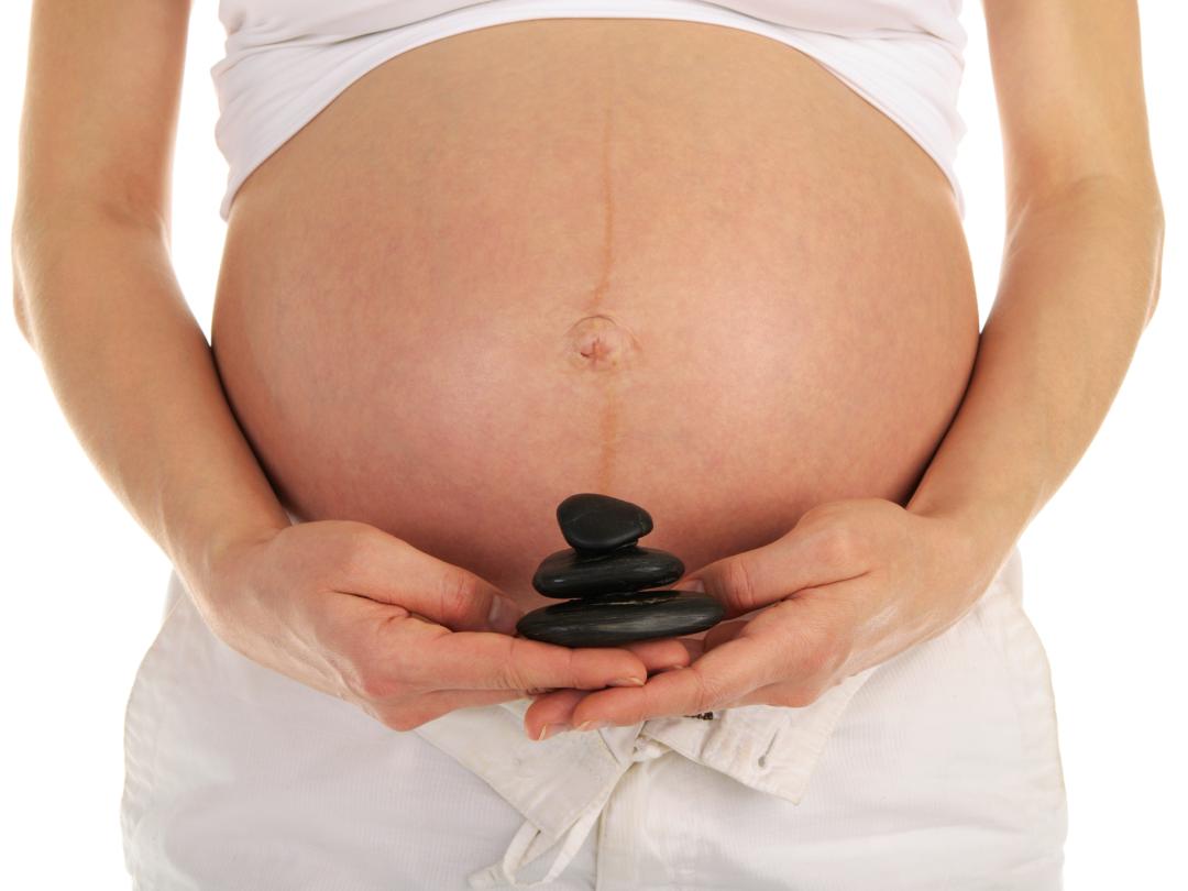 Vrouw met stenen in de hand voor zwangere buik