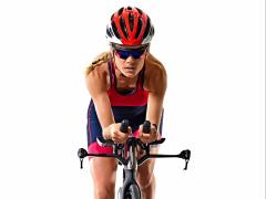 Een wielrenner zit voorover gebogen op haar fiets.