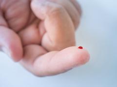 Een vinger met een druppel bloed.