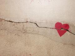 Een getekend hart op een muur of vloer. De ondergrond is gebarsten en de barst loopt door het hart heen.