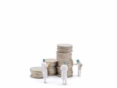 Drie poppetjes staan naast stapels munten.