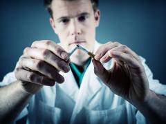 Een man breekt een sigaret doormidden.