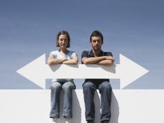 Twee mensen zitten op een muur en houden een pijl vast. De pijl wijst zowel naar links als naar rechts.