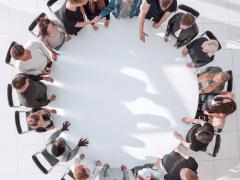 Een groep mensen zit aan een ronde tafel.