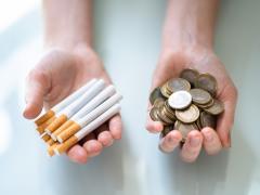 Eén hand gevuld met sigaretten. de andere met geld