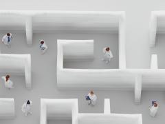 Meerdere mensen in een wit doolhof van bovenaf gezien.