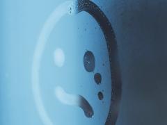 Een beslagen ruit met een ongelukkige smiley erop getekend