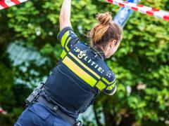 Een politieagent die cordon omhoog houdt