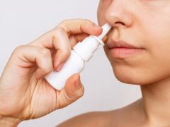 Een vrouw die neusspray in haar neus sprayt