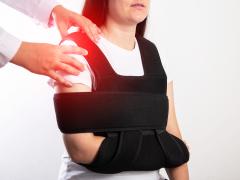 Een arts die aan de schouder zit van een vrouw in mitella